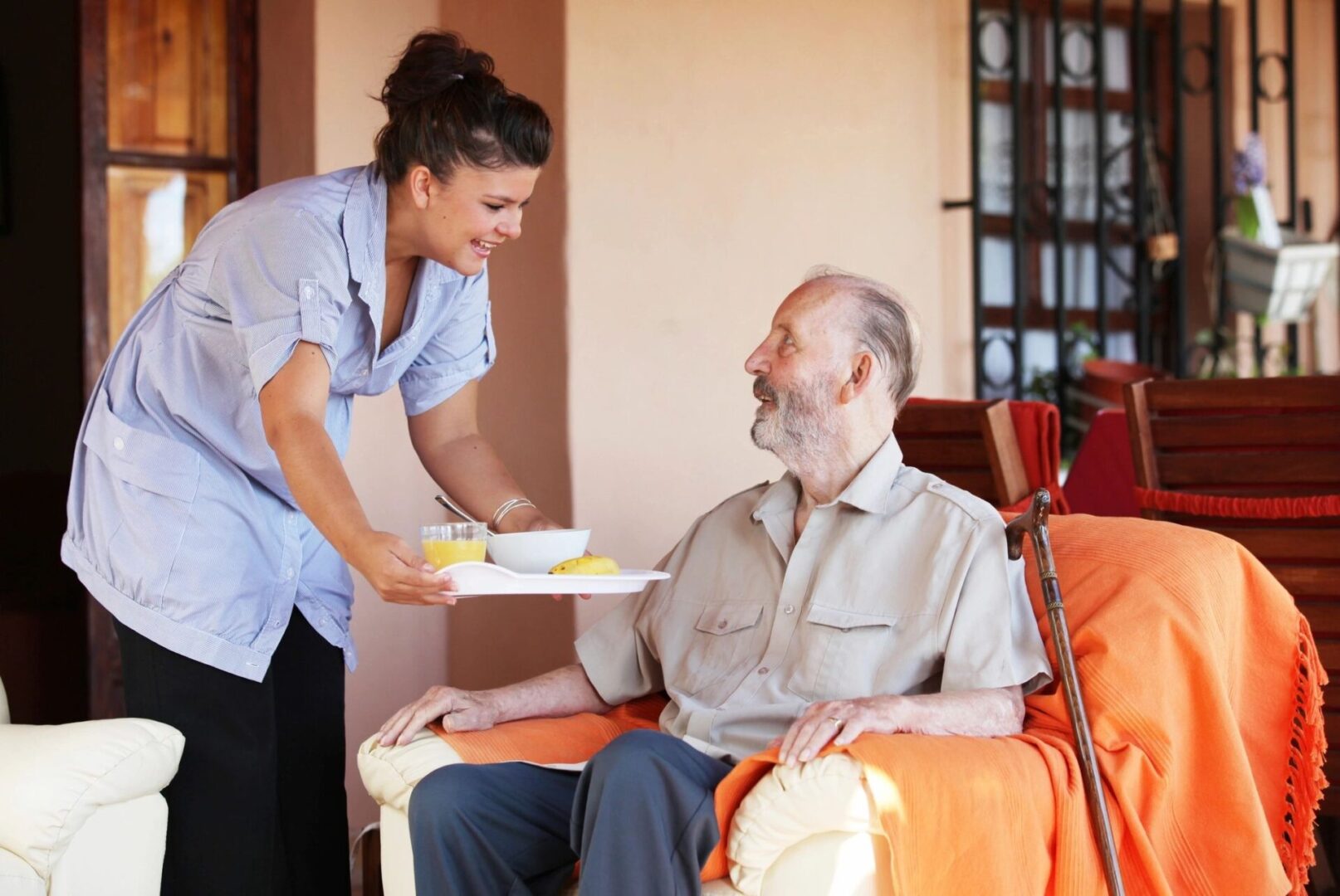 a nurse delivering food to an old man