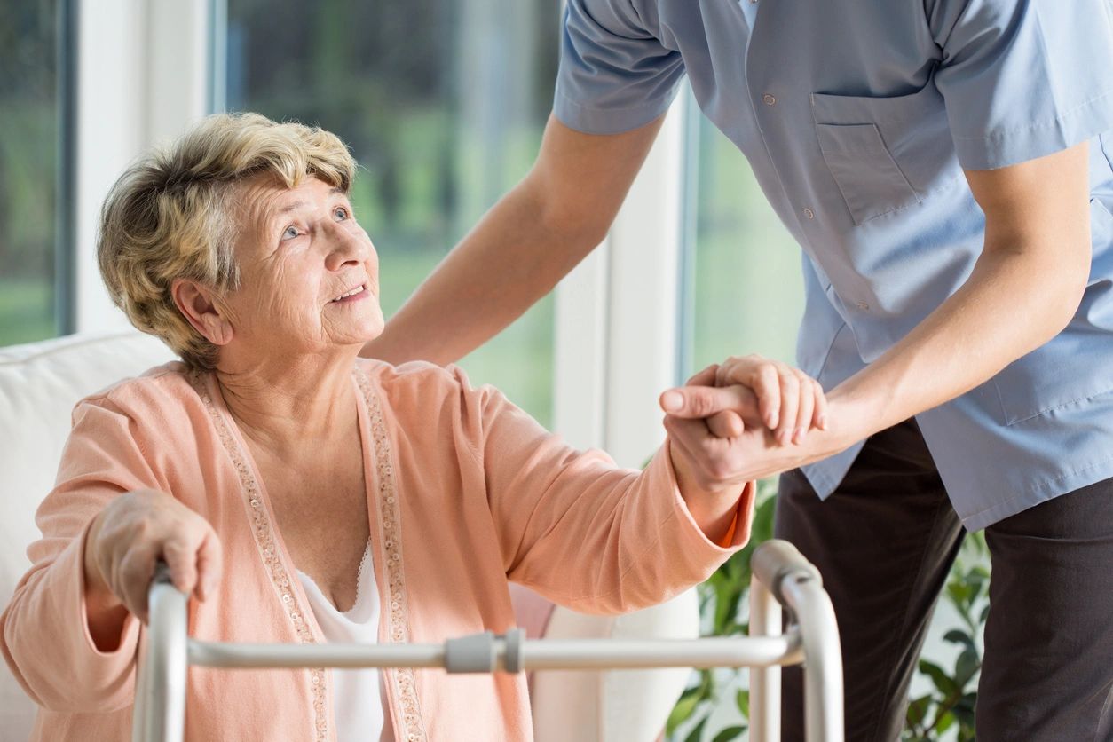 a nurse helping an old woman stand